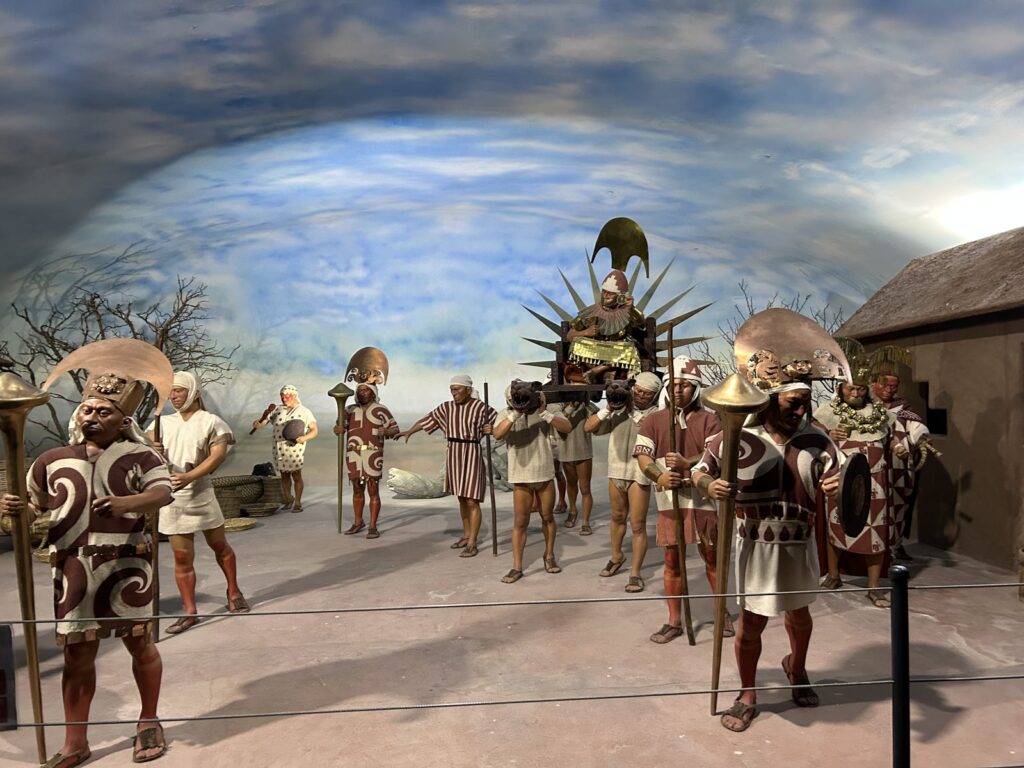 Diorama de museo con una procesión andina: cargadores llevando una litera con un personaje ceremonial