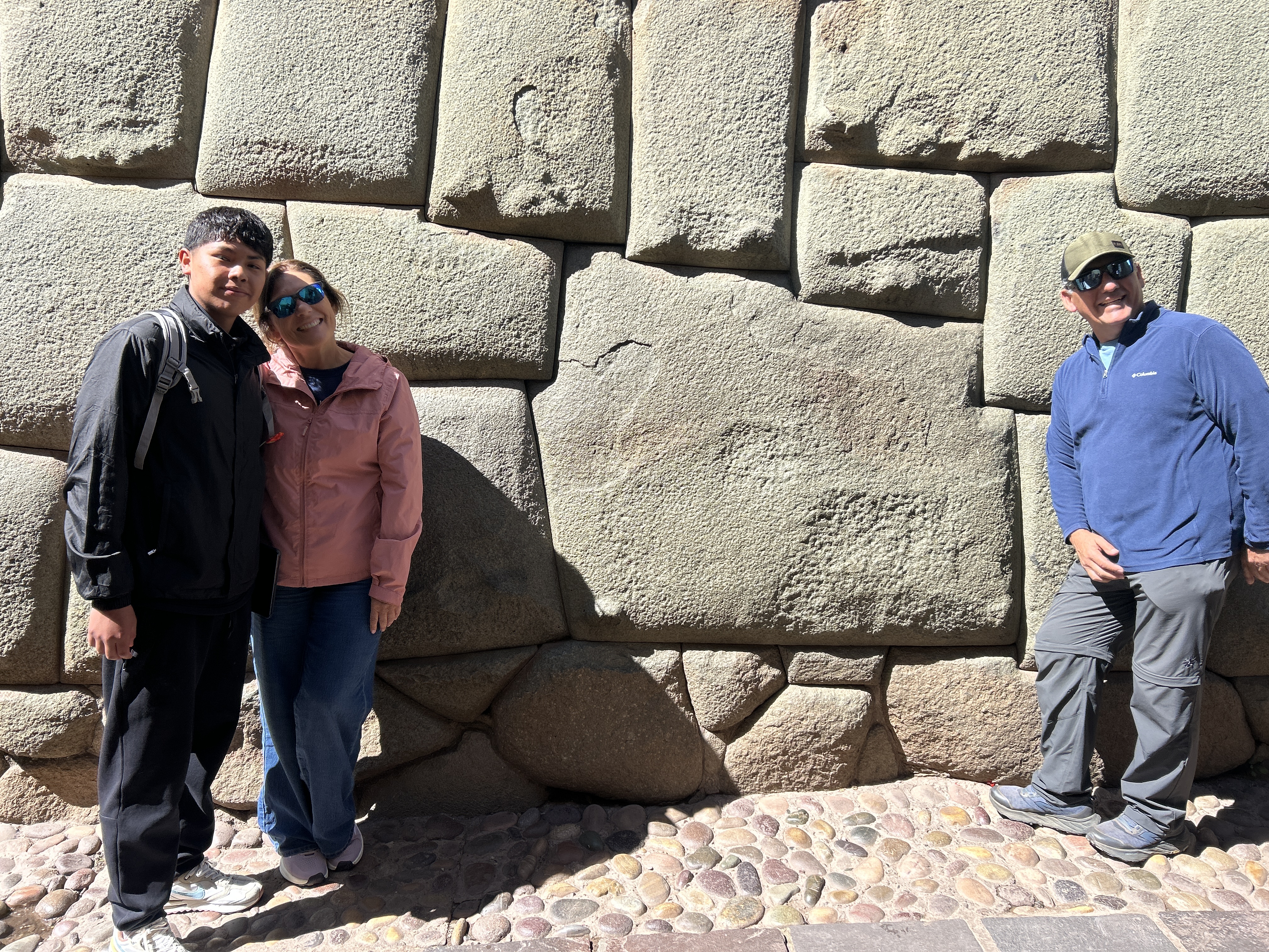 Visitantes frente a un muro inca de piedras perfectamente encajadas en Cusco