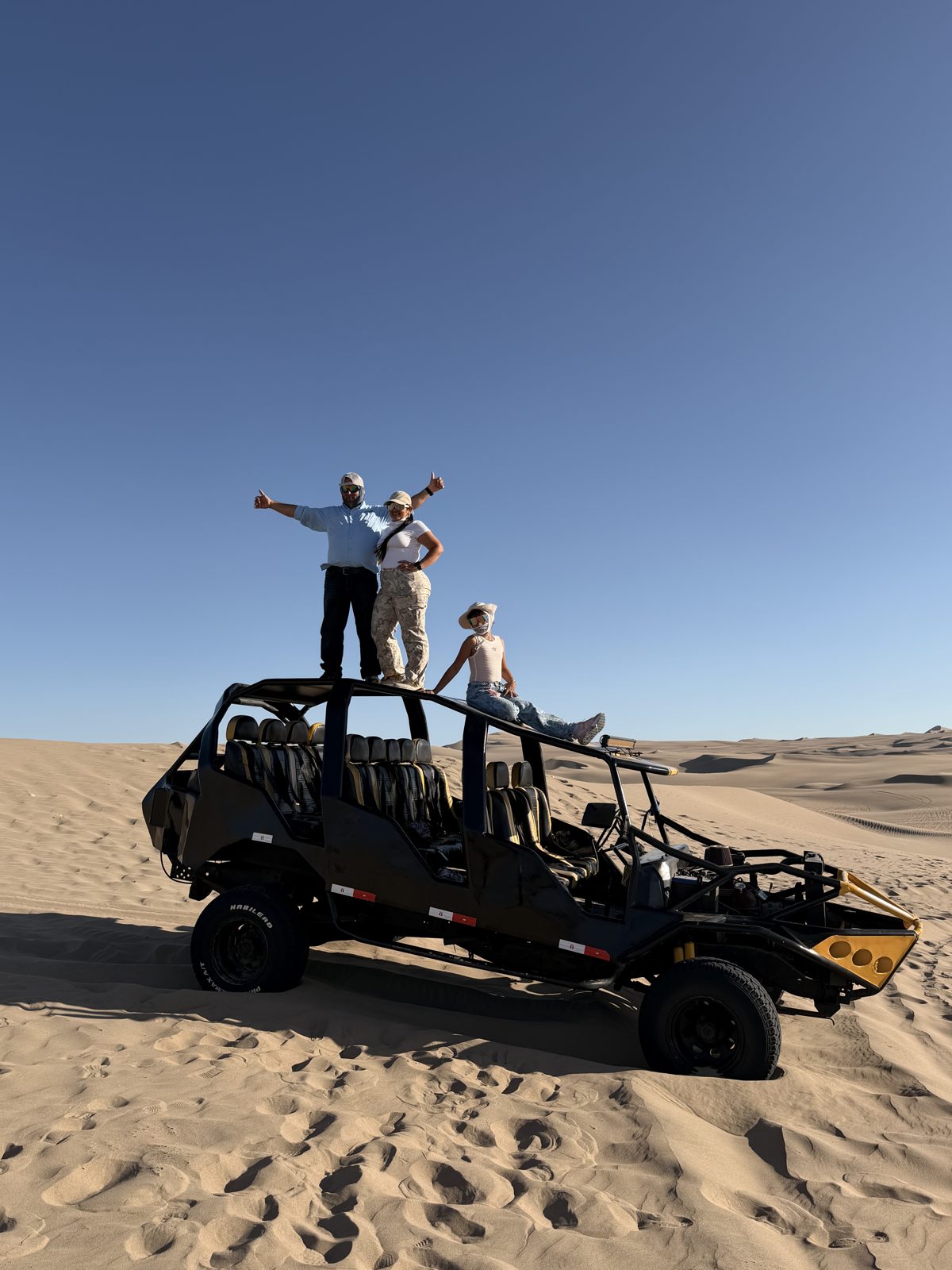 Buggy sobre las dunas de Huacachina con viajeros de pie sobre el vehículo